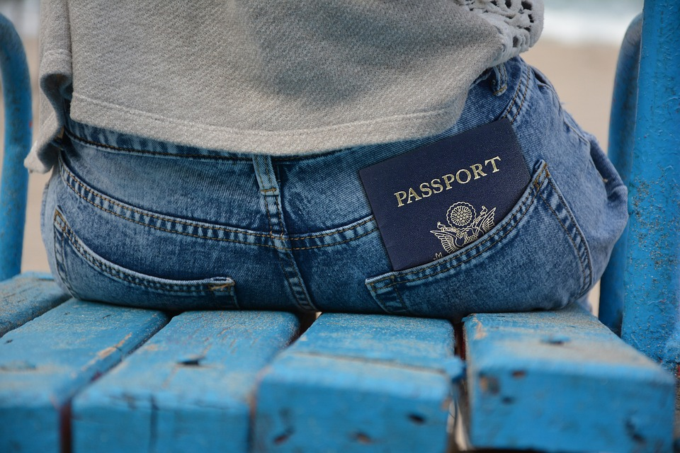 a woman sitting on a blue bench with her passport tucked away in her pocket